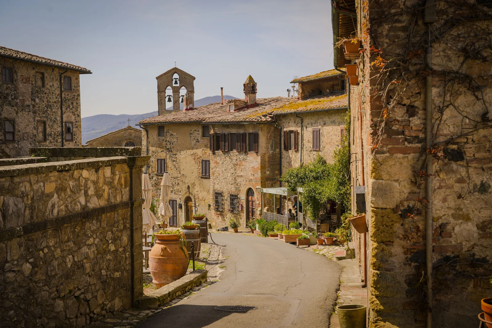 A sunlit street and stone buildings in a Tuscan village