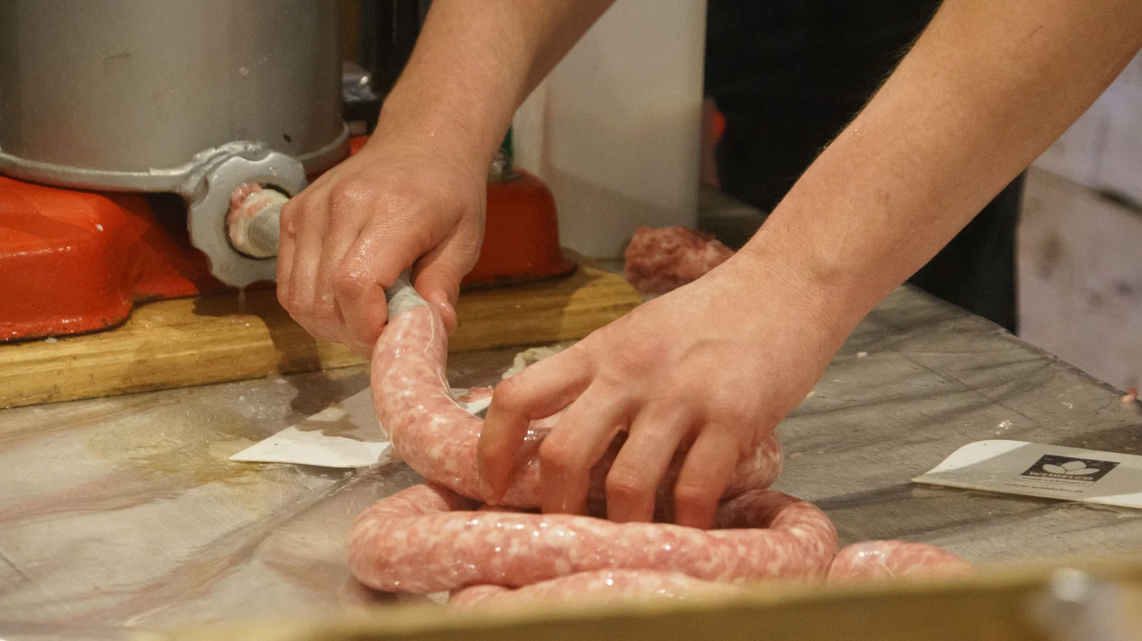 Hands filling sausage casings at a kitchen work surface